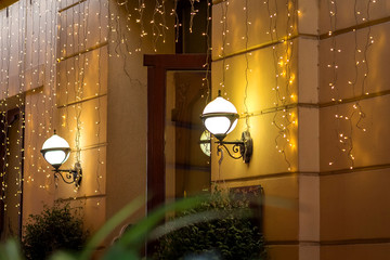 Lamps and garlands on the wall of the house during Christmas and New Year holidays_