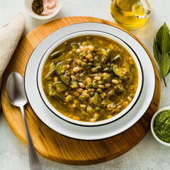 gluten free green minestrone with cannellini beans. on the table with spices and arugula pesto. Traditional Italian Tuscan soup. healthy food for the whole family on the blue table
