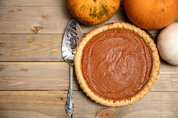 top down shot of a freshly baked pumpkin pie surrounded by pumpkins
