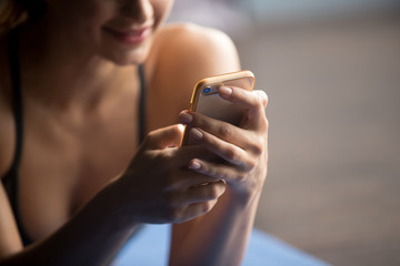 Young attractive woman after practicing yoga, relaxing on yoga mat, using app, making a call,...