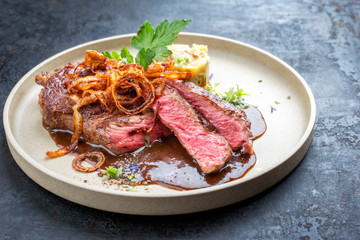 Modern design dry aged sliced roast beef with fried onion rings and mashed potatoes as closeup on a...