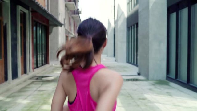 Slow motion - Healthy beautiful young Asian runner woman in sports clothing running and jogging on street in urban city. Lifestyle fit and active women exercise in the city concept.