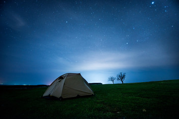 Camping tent in the night mountains under a starry sky