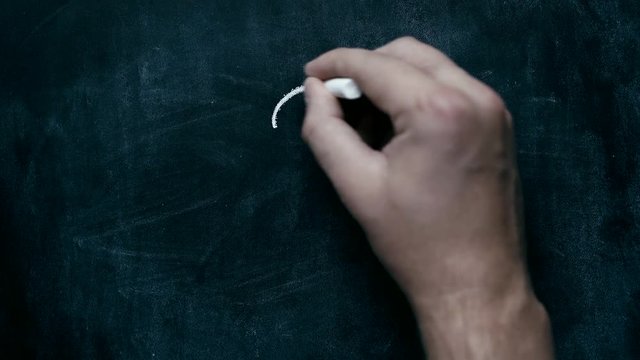 Hand writes with chalk "question mark" on blackboard
