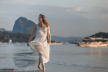 Woman in white dress at the sea on the sunset on Palawan island, Philippines