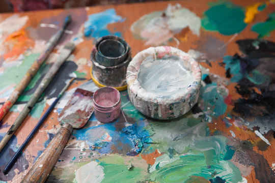 Oil paints and paint brushes on a palette, in the studio of artist.