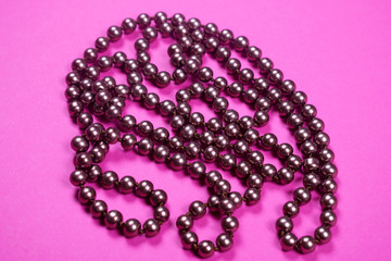 Brown shiny necklace on a pink background,