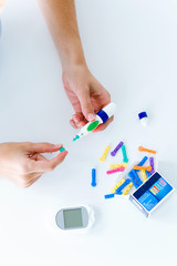 Young woman changing pencil needle to get tested for glucose on white background.