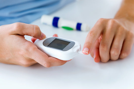 Young woman getting glucose test with glucometer at home.