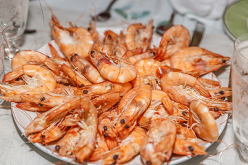Plate with many freshly cooked and appetizing prawns, on a table prepare for a celebration