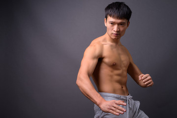 Young shirtless Chinese man against gray background