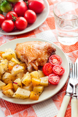 Baked chicken thigh with baked potatoes and pumpkin garnish on a plate