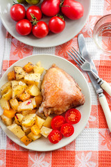 Baked chicken thigh with baked potatoes and pumpkin garnish on a plate