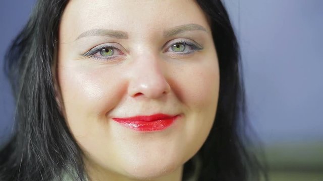 Face of a smiling woman with bright red lipstick.