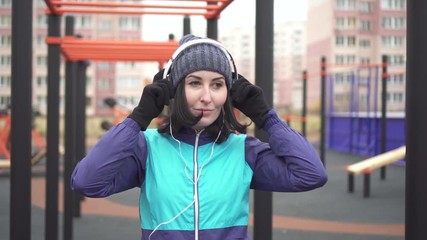 Woman athlete with headphones on the street playground