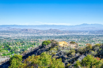 Dirt road above inland city of California with houses and blue sky
