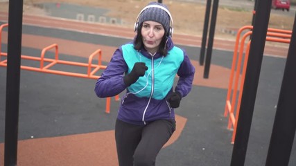 Woman athlete in headphones doing workout on the street playground