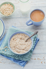Oatmeal porridge bowl on the white wooden background.