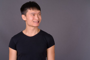 Studio shot of young Chinese man against gray background