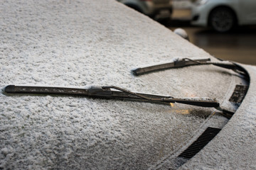 Closeup of wipers and frosted car windshield covered with ice and snow.  Winter weather,...
