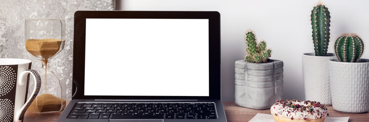 Panoramic photo of hipster desk with laptop mockup, cup of coffee, hourglass, donut, cactuses in concrete pots and stone on the wall