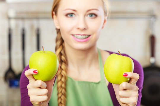 Woman young housewife in kitchen with apple fruit