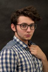 serious young man with glasses on black background.