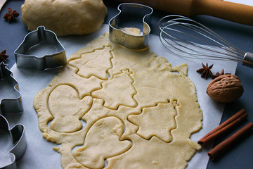 Christmas cookies. Cutting gingerbread. The process of baking cookies at home. Gingerbread dough for cookies, cookies, cinnamon sticks, orange and fir branches. New year or winter holidays still life,