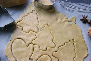 Christmas cookies. Cutting gingerbread. The process of baking cookies at home. Gingerbread dough for cookies, cookies, cinnamon sticks, orange and fir branches. New year or winter holidays still life,