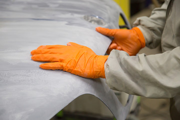 Repair and painting car car mechanic. Auto mechanic worker painting car in a paint chamber during repair work. Auto repairman plastering autobody bonnet. 