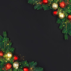 The branch of a Christmas tree with xmas decorations and magical stardust on a black background