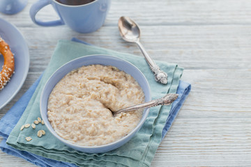 Oatmeal porridge bowl on the white wooden background.