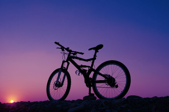 Silhouette of mountain bicycle against sunset. Toned image