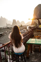 Foto op Canvas Yangshuo, China Mountainous Landscape Exotic Asian Sunset Travel.girl watching sunset on the roof of the house © ritiniya