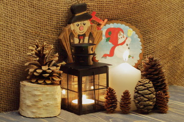 Christmas is coming. Lighted candles, black metal lantern, fir cones, wooden chimney sweeper and...