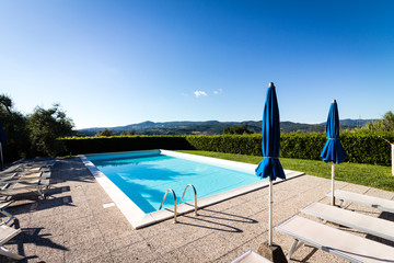 Leerer Swimmingpool vor blauem Himmel in der Toscana - 230888862