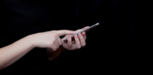 Hand holding and Touching a Smartphone isolated on black background