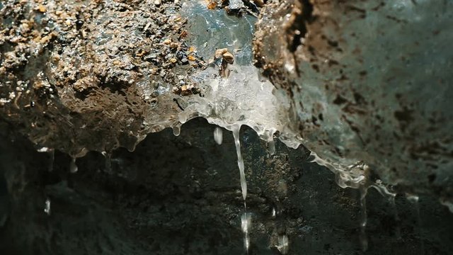 Water flows from the melting glacier close up, spring drops slow motion