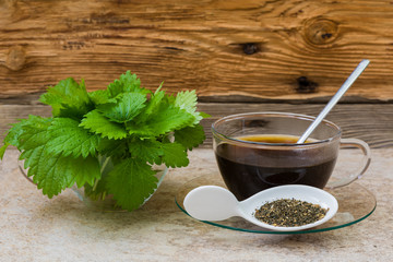 Taza con infusión de ortiga, semillas y hojas verdes