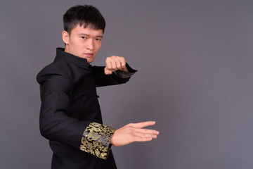 Studio shot of young Chinese man against gray background