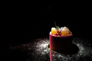Tasty red cake with fruit on a black background