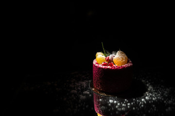 Tasty red cake with fruit on a black background
