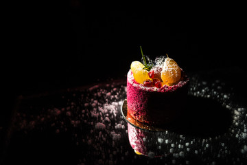 Tasty red cake with fruit on a black background