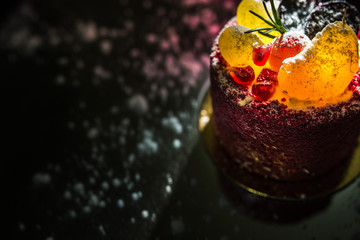 Tasty red cake with fruit on a black background
