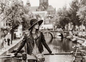 Redhead in hat staying on bridge in Amsterdam. Image in black and white color style