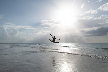 jump on the ocean beach against the blue sky and the sun