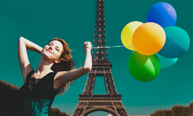 Redhead girl with colour balloons on parisian Eiffel tower background.