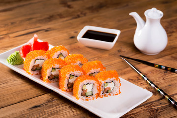 sushi in a white plate lie on a wooden table