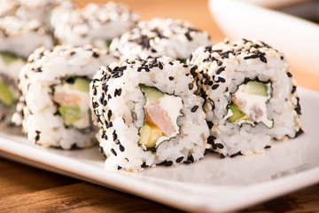 sushi in a white plate lie on a wooden table