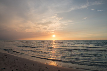 Naklejka na ściany i meble sandy beach by the ocean at sunset
